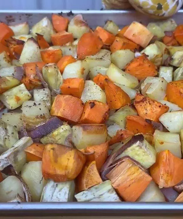 Roasted sweet potatoes and eggplants on a baking sheet, seasoned and cooked to perfection.