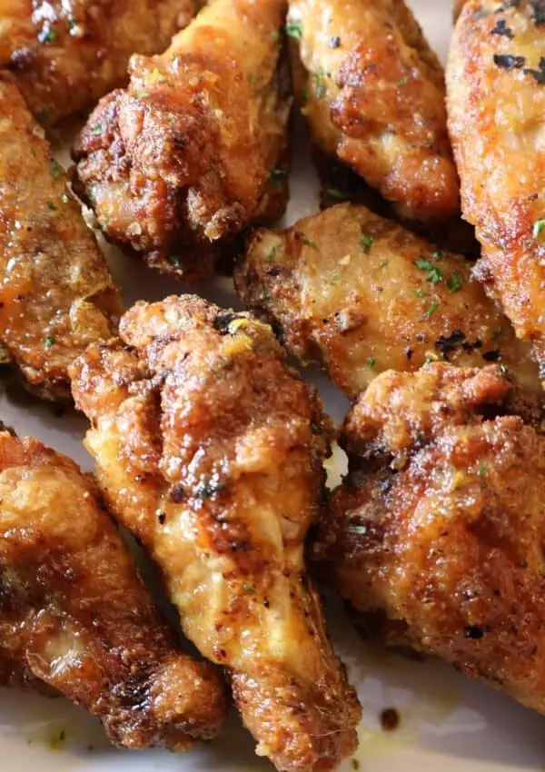 Crispy golden-brown chicken wings with herbs and spices on a plate.