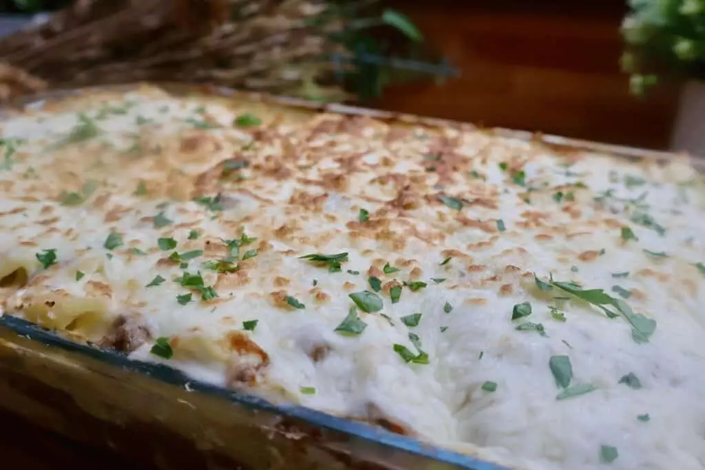 Delicious homemade baked lasagna topped with cheese and fresh herbs in a glass dish.