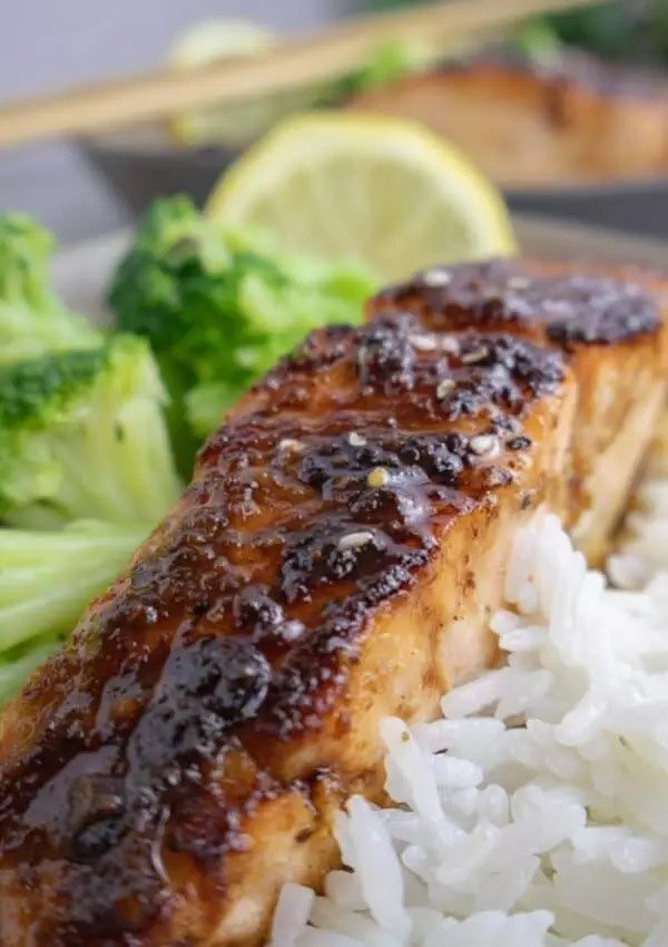 Grilled salmon with rice and broccoli, garnished with lemon, on a plate. Perfect for a healthy meal option.