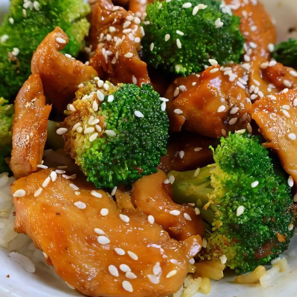 Stir-fried chicken and broccoli topped with sesame seeds over rice, a delicious and healthy Asian-inspired dish.