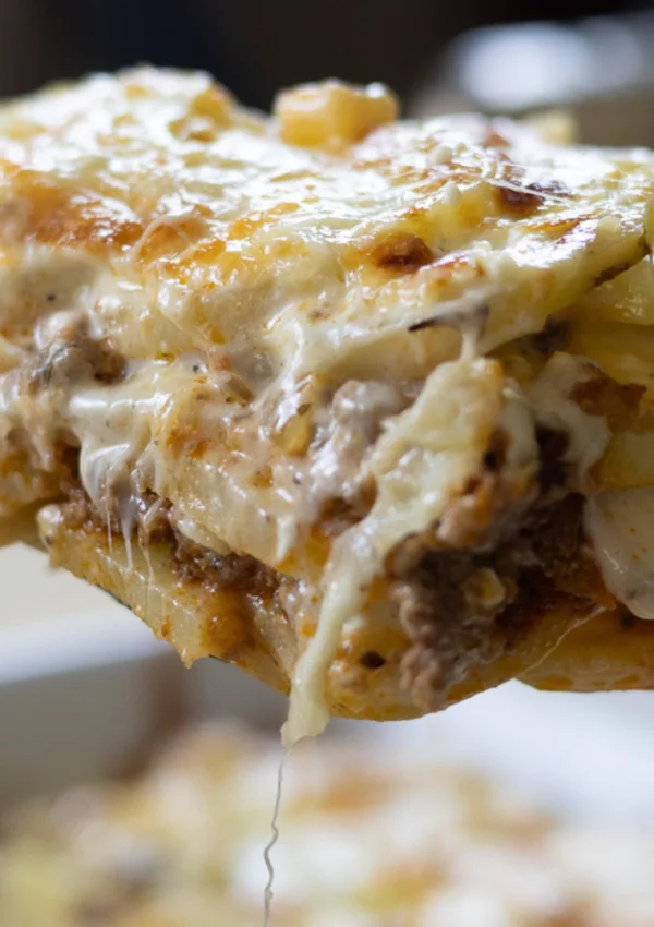 Close-up of a cheesy lasagna slice with layers of pasta, meat, and cheese melting together.