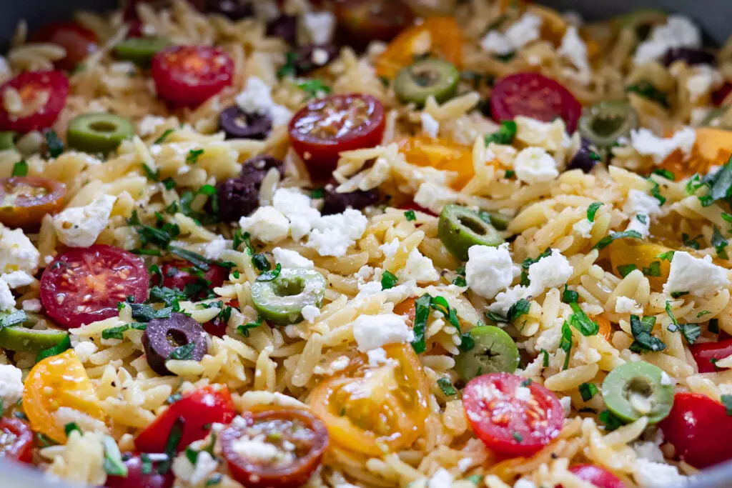 Delicious mediterranean orzo pasta salad with cherry tomatoes, olives, feta cheese, and fresh herbs. Perfect Mediterranean dish.